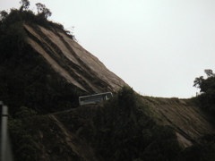 A bus passes in front of a slaty rock face on the WMDR