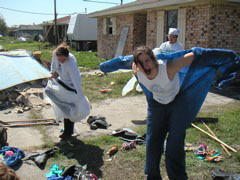 The work we did was "gutting" houses, which meant take everything out of the house, knock down the walls, ceiling, carpets, etc, and put it all into a big junk pile on the front yard.  Since everything was full of toxic mold, mud, and dust, we had protective gear.  First, full-body tyvek suits such as the one Katie is donning in dinosaur fashion.